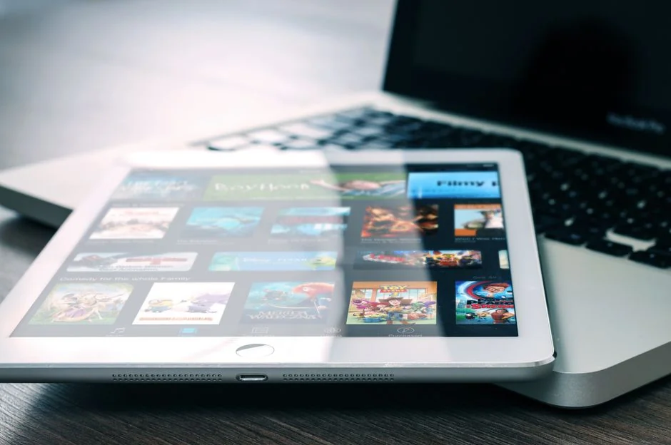 Un homme retouche l’image d’un fruit sur un MacBook Pro, assis dehors sur l’herbe.
